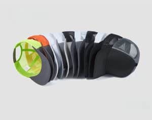 A dynamic fanned-out arrangement of multi-colored blank trucker hats (neon, orange, grey, black) on a white background, demonstrating US stock variety.